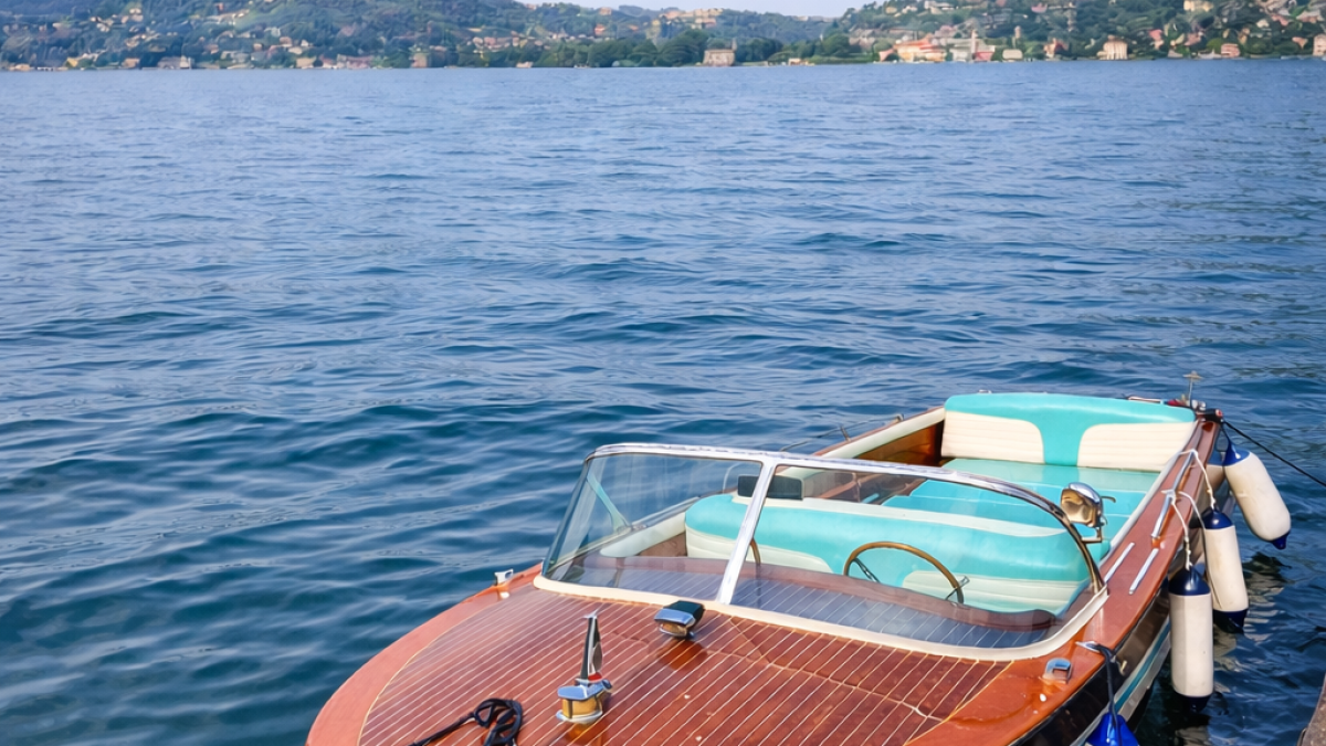 Wooden speedboat docked on a calm lake with hills in the background.