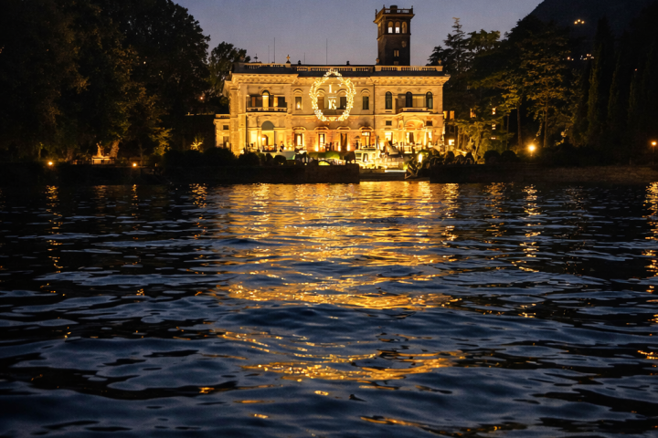 Illuminated building near water at dusk with reflections on the surface.