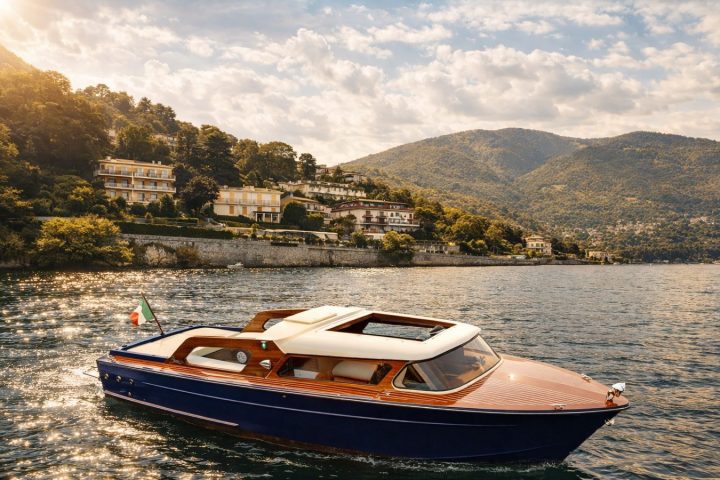 Blue and wooden boat on Lake Como with mountains and villas in the background.