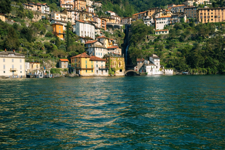Hillside village with colorful houses by a lake under a blue sky.